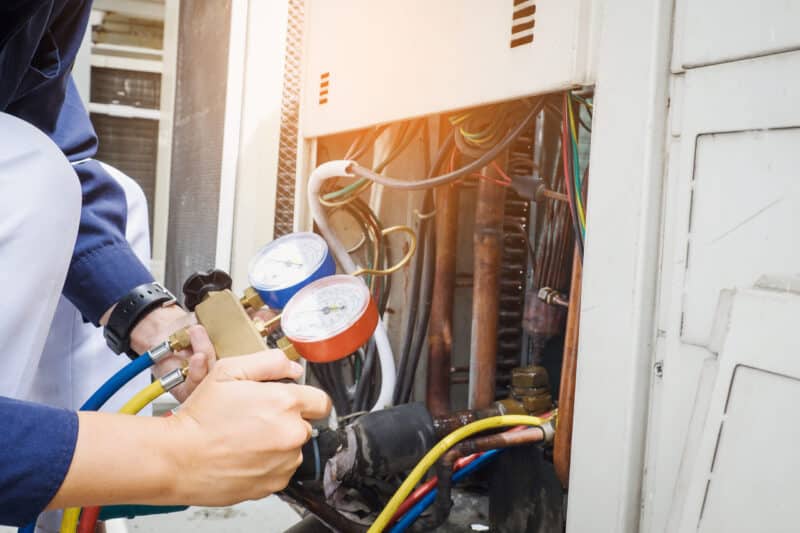 Technician repairing an air conditioning unit with professional tools, ensuring efficient AC performance and reliability. Expert AC repair services by Grizzly Heating and Air.